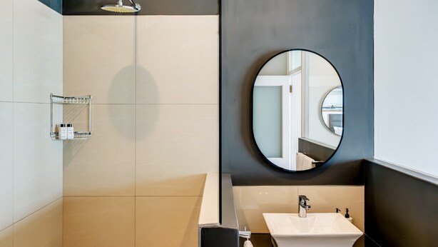 Un bagno moderno con doccia, lavandino e specchio.