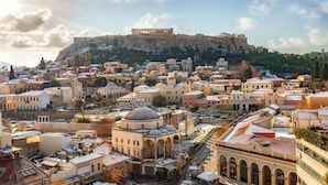 Un paysage urbain d’importance historique, dominé par une ancienne forteresse située sur une colline, et entouré de bâtiments traditionnels aux toits en dôme et aux arcades.