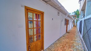 A narrow corridor with a tiled floor and a wooden door with glass panels.