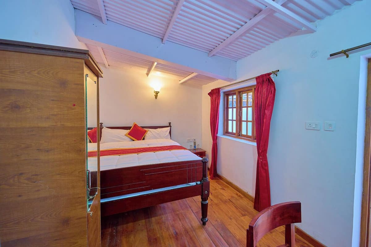 A bedroom with a wooden bed, a nightstand, a wardrobe, and a window with red curtains.