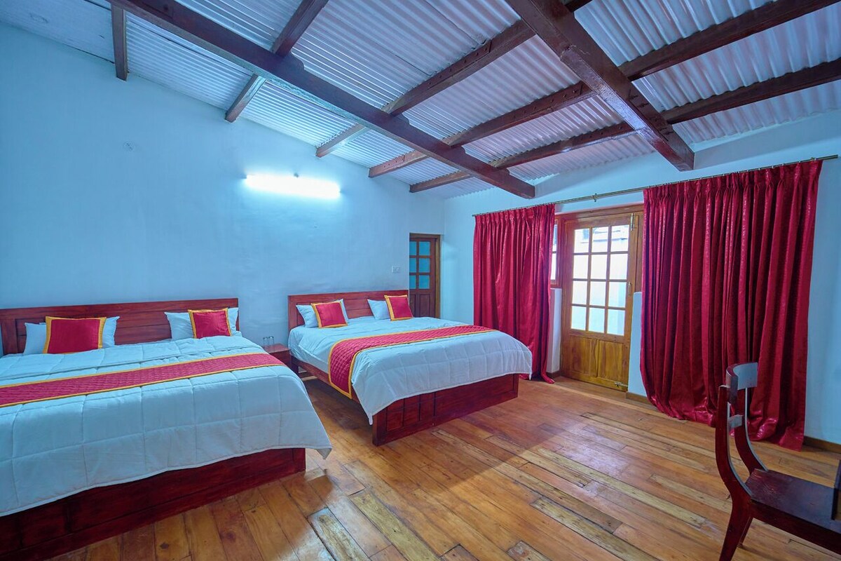 A room with two wooden beds, red curtains, and a wooden chair.