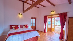 A bedroom with a wooden bed, a red curtain, and a view of the outside.
