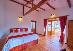 A bedroom with a wooden bed, a red curtain, and a view of the outside. - Shivvs Heritage Resort Ooty (Ootacamund)