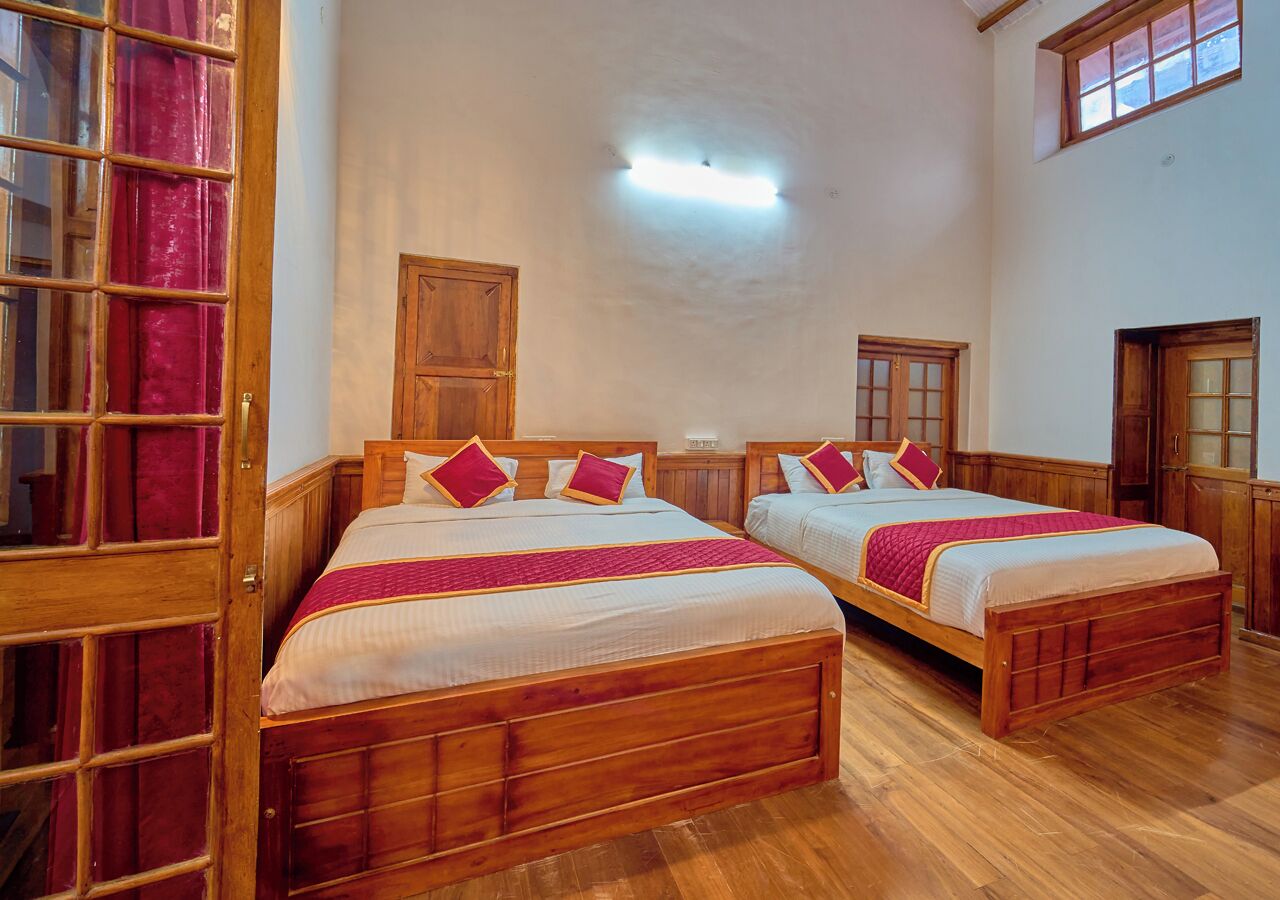 A room with two wooden beds, a wooden wardrobe, and a door with a glass panel.