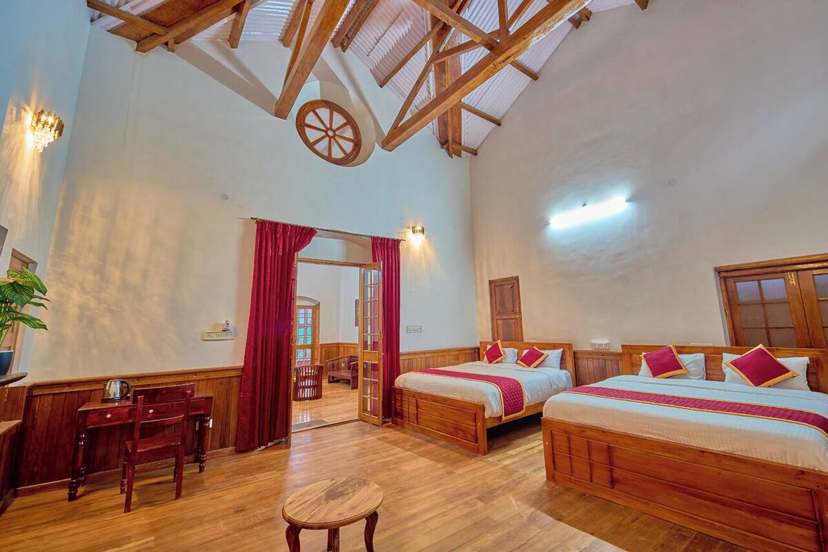 A spacious room with two wooden beds, a wooden desk, and a chair.