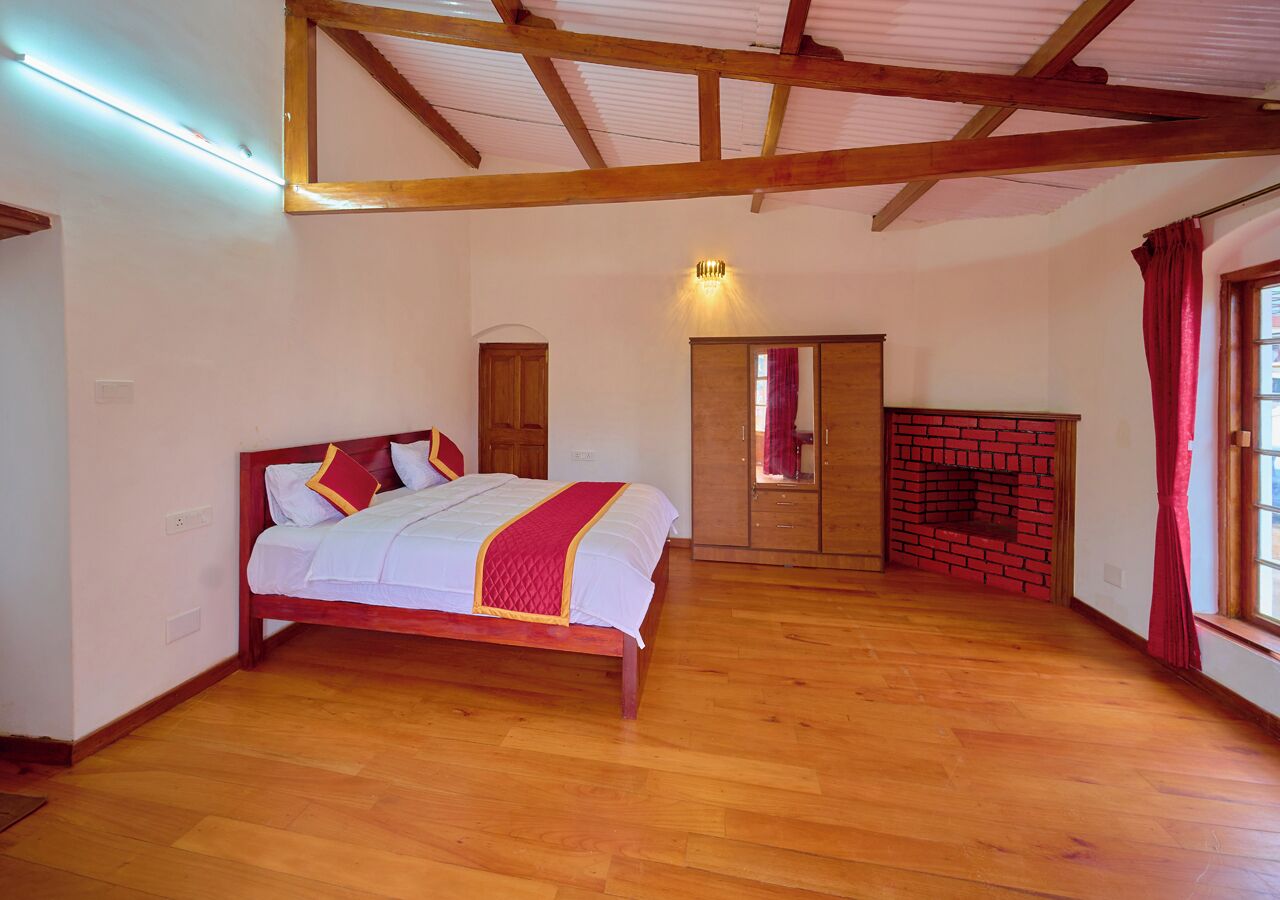 Una camera da letto con un letto di legno, un camino in mattoni e un'ampia finestra con tende.
