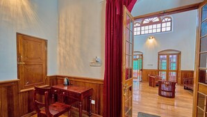 Una habitación con muebles de madera, una cortina roja y vistas a otra habitación con bancos de madera a través de un ventanal.