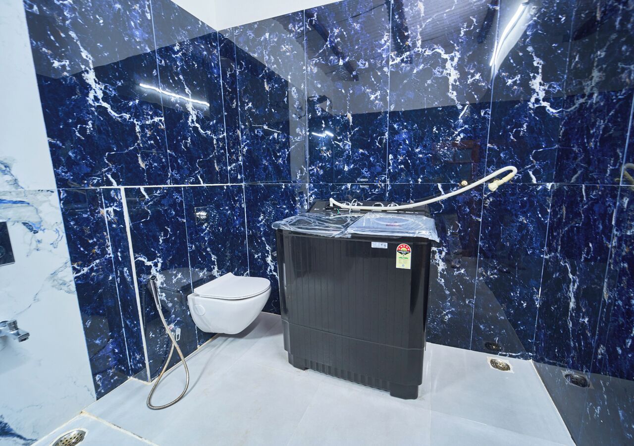 Une salle de bain avec des toilettes blanches, un chauffe-eau noir et des carreaux de marbre bleus.