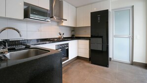 A modern kitchen with white cabinets, a stainless steel range hood, a black refrigerator, and a built-in oven. - w Magnificent 3BR in the Heart of Barranco (Lima)