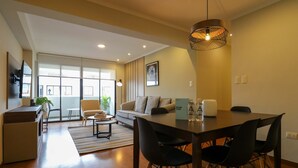 A modern living room with a dining area, a sofa, a coffee table, and a TV. - w Magnificent 3BR in the Heart of Barranco (Lima)