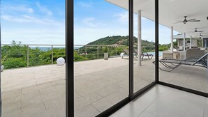 Ein moderner Balkon mit freiem Blick auf eine Hügelkuppe und das Meer.