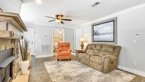 A living room with a fireplace, a ceiling fan, a large window with a view, and a plush sofa. - Chattanooga House w/ Grill: 12 Mi to Downtown! (Chattanooga)