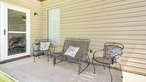 A covered patio with metal chairs and a bench, a sliding glass door, and a window with blinds. - Chattanooga House w/ Grill: 12 Mi to Downtown! (Chattanooga)