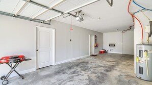 A garage with a concrete floor, a red grill, and a water heater. - Chattanooga House w/ Grill: 12 Mi to Downtown! (Chattanooga)