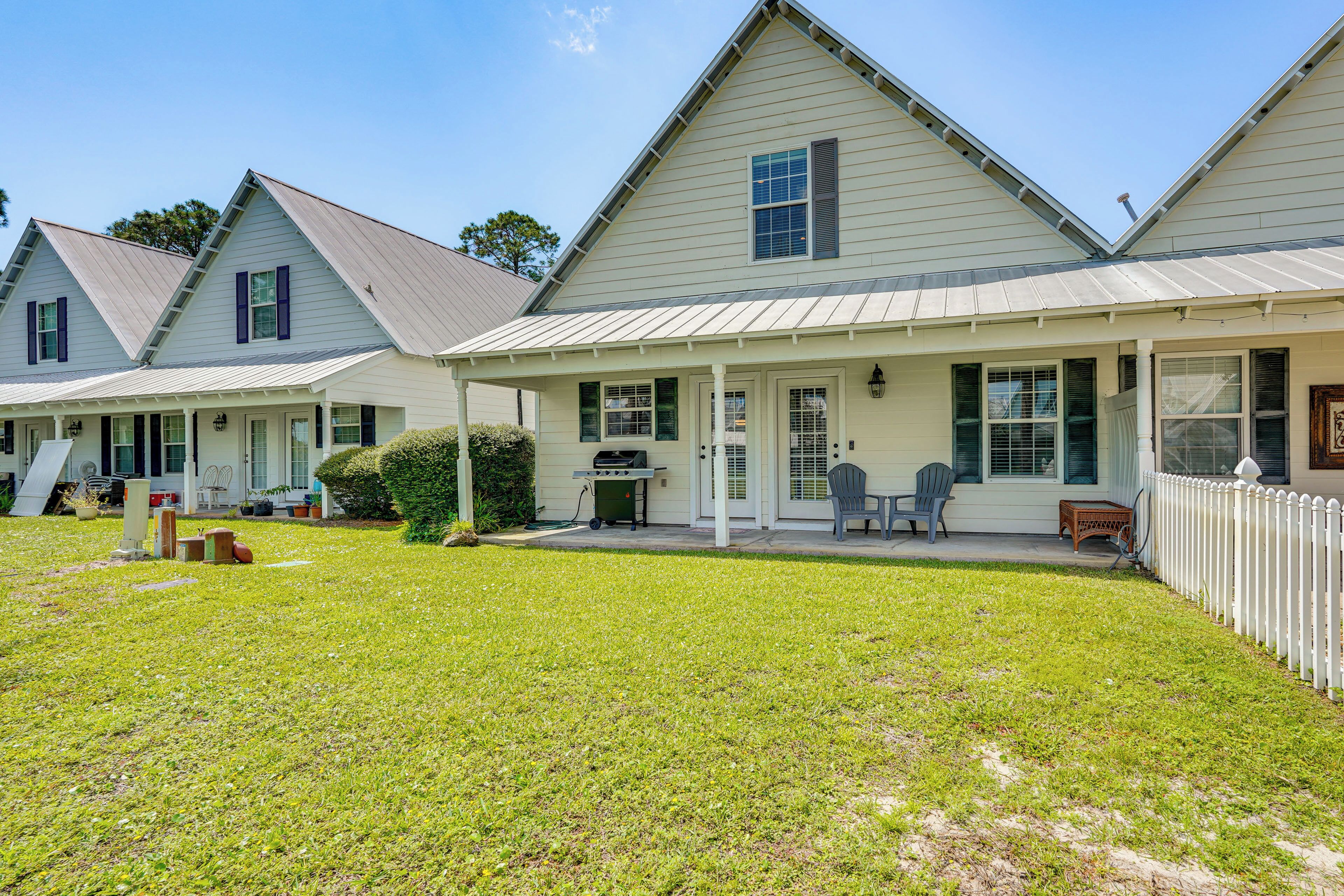 A row of single-story houses with a porch and a grill, surrounded by a well-maintained lawn.
