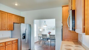 A kitchen with wooden cabinets, a stainless steel refrigerator, a dining table with chairs, and a built-in stove. - Walk to Bay & Dtwn: Port St Joe Paradise w/ Grill! (Port St. Joe)