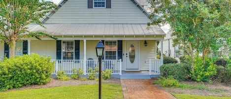 A single-story house with a front porch, a small garden, and a brick pathway leading to the entrance.