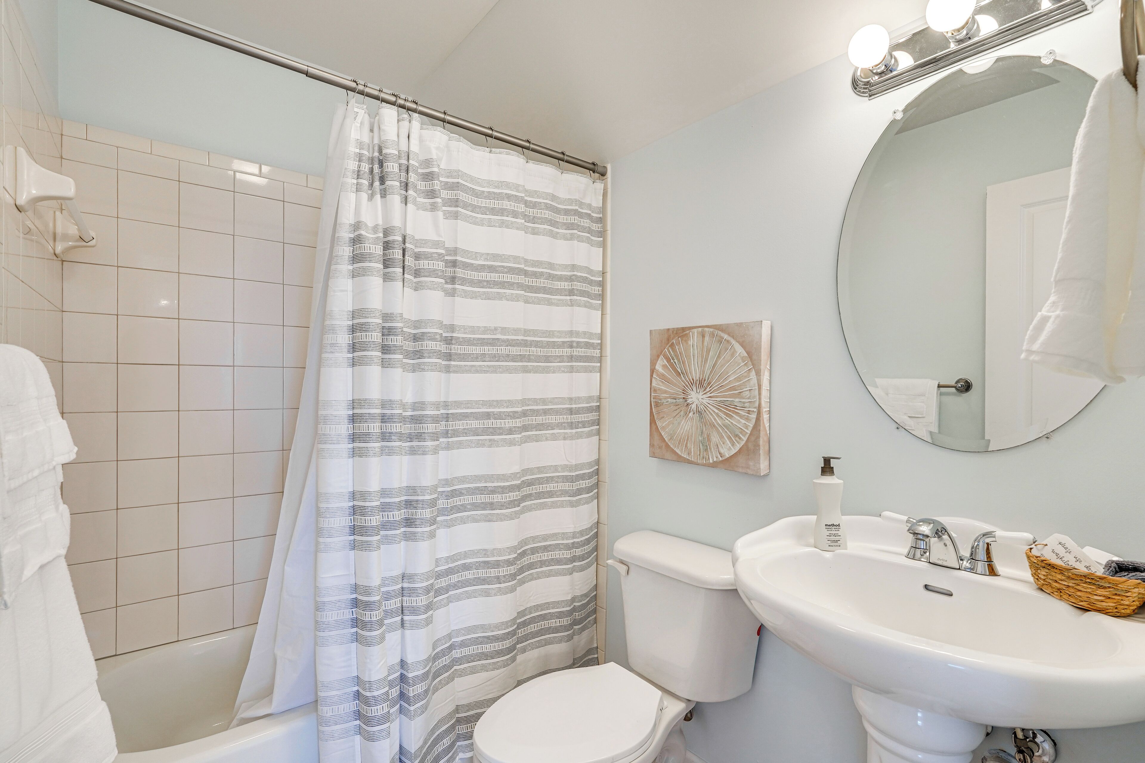 Un baño con ducha, inodoro, lavamanos y espejo con iluminación.
