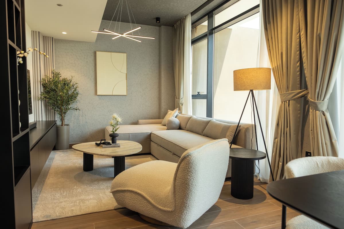 A modern living room with a sectional sofa, a round coffee table, a floor lamp, and a potted plant.