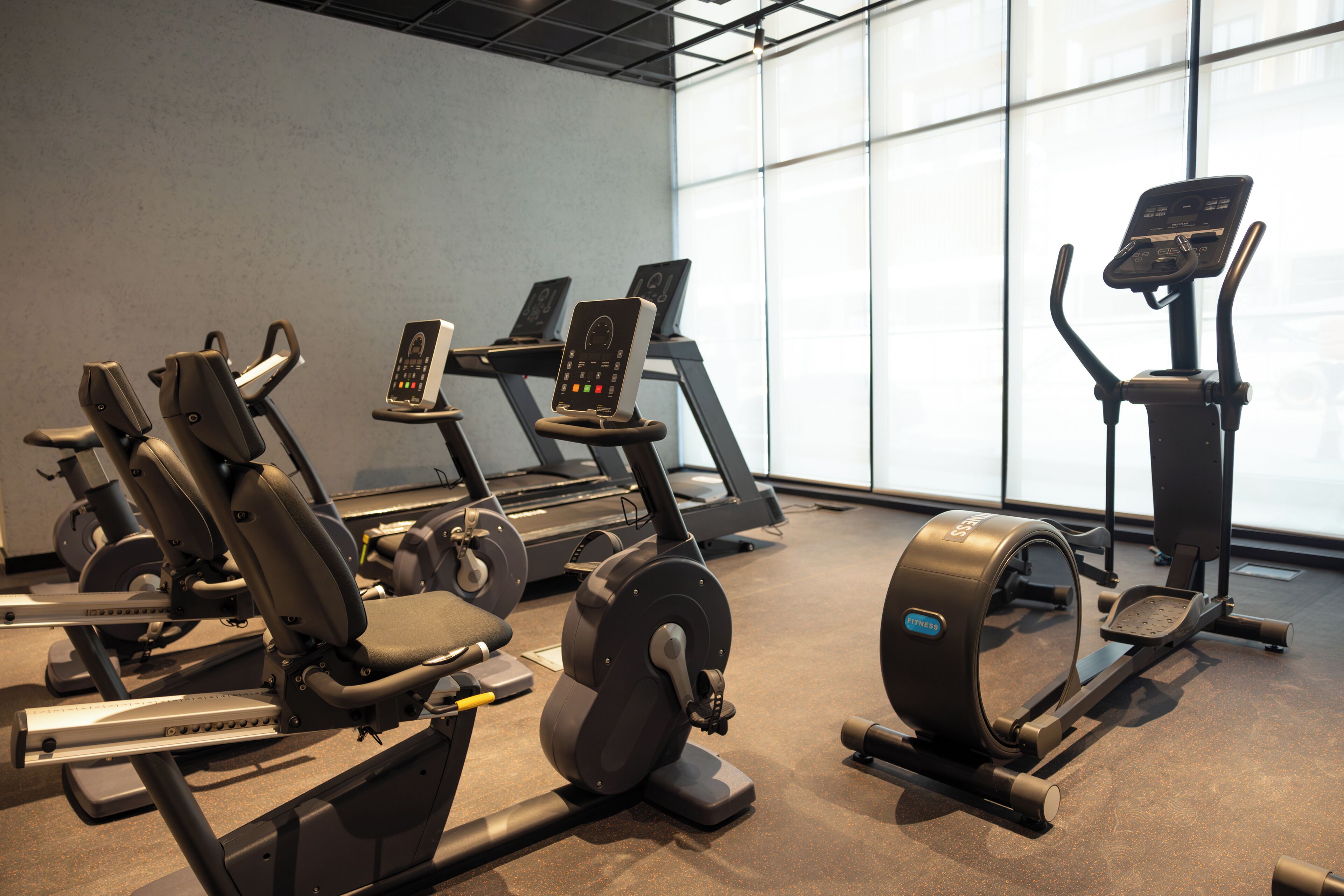 Une salle de sport équipée de divers appareils d’exercice, notamment des tapis de course, des vélos d’appartement et des appareils de musculation elliptique.