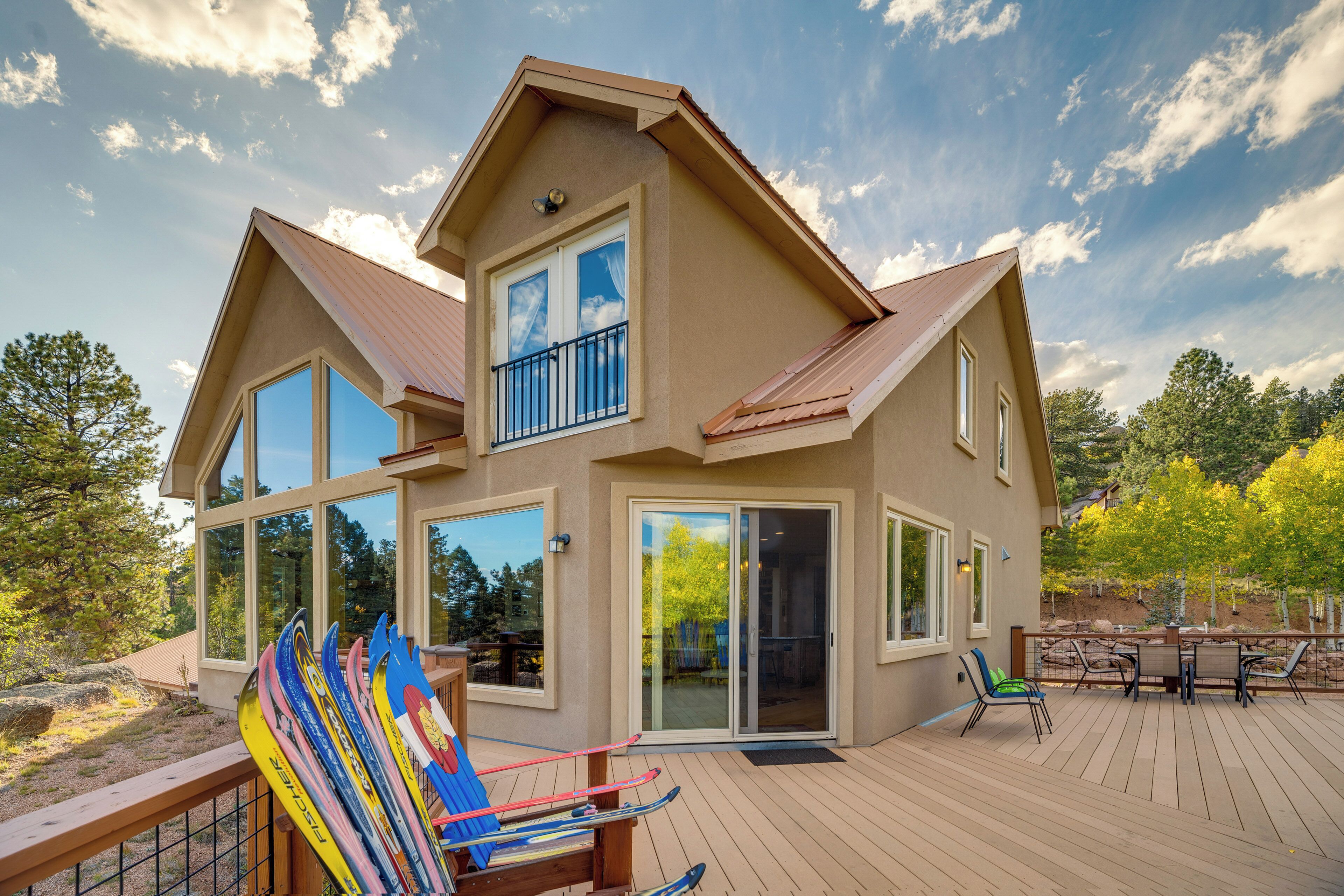 A two-story house with large windows, a deck, and a patio area.