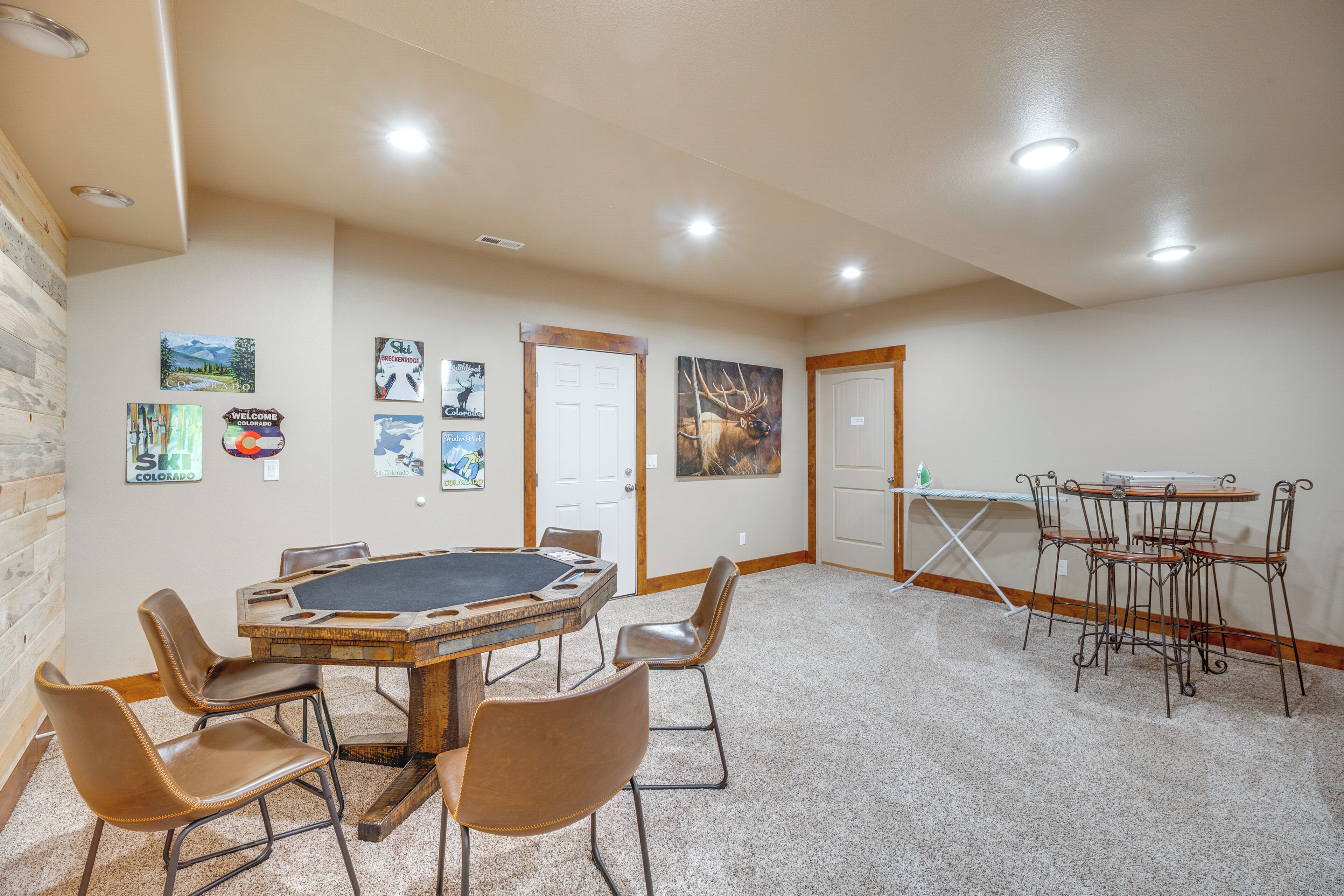 A room with a wooden table and chairs, a white door, and wall art.