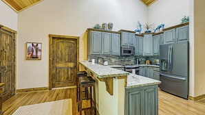 Eine Küche mit Holzausstattung, einer Granitarbeitsplatte und einem Edelstahlkühlschrank.