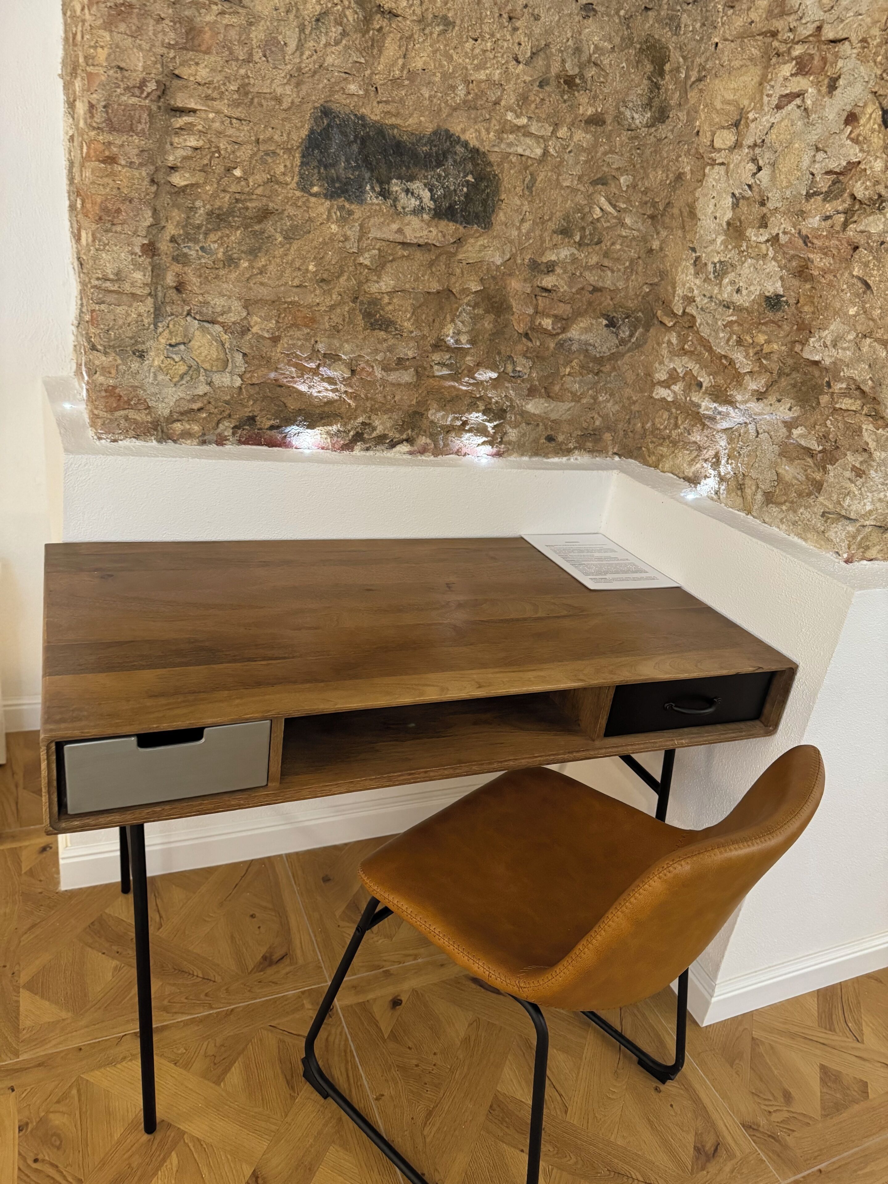Un escritorio de madera con un cajón y una silla marrón con patas de metal.