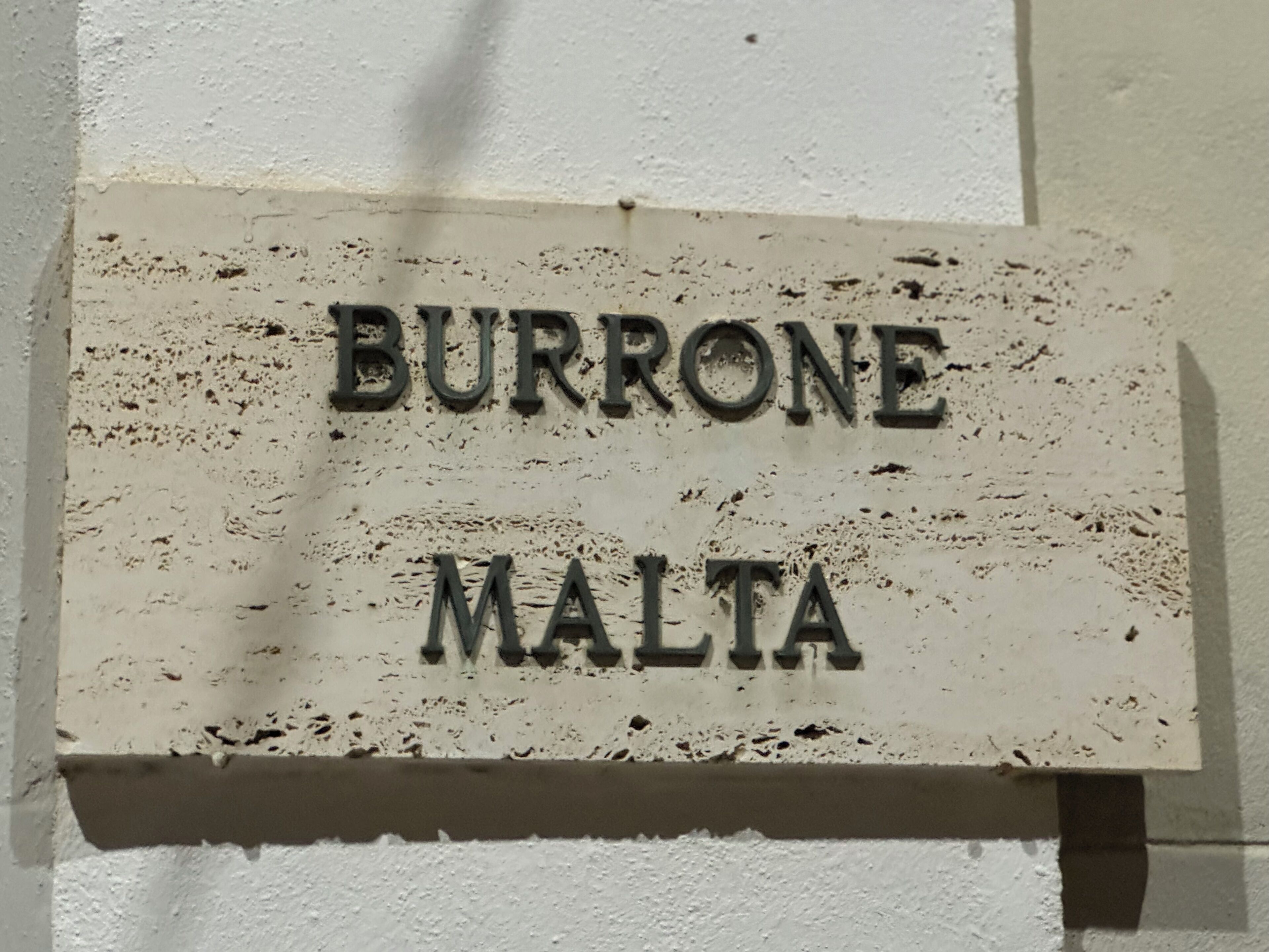 Une enseigne avec le texte « BURRONE MALTA » sur un fond blanc.