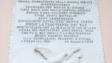 A marble plaque with text commemorating General Giuseppe Malta, highlighting his military achievements and contributions.