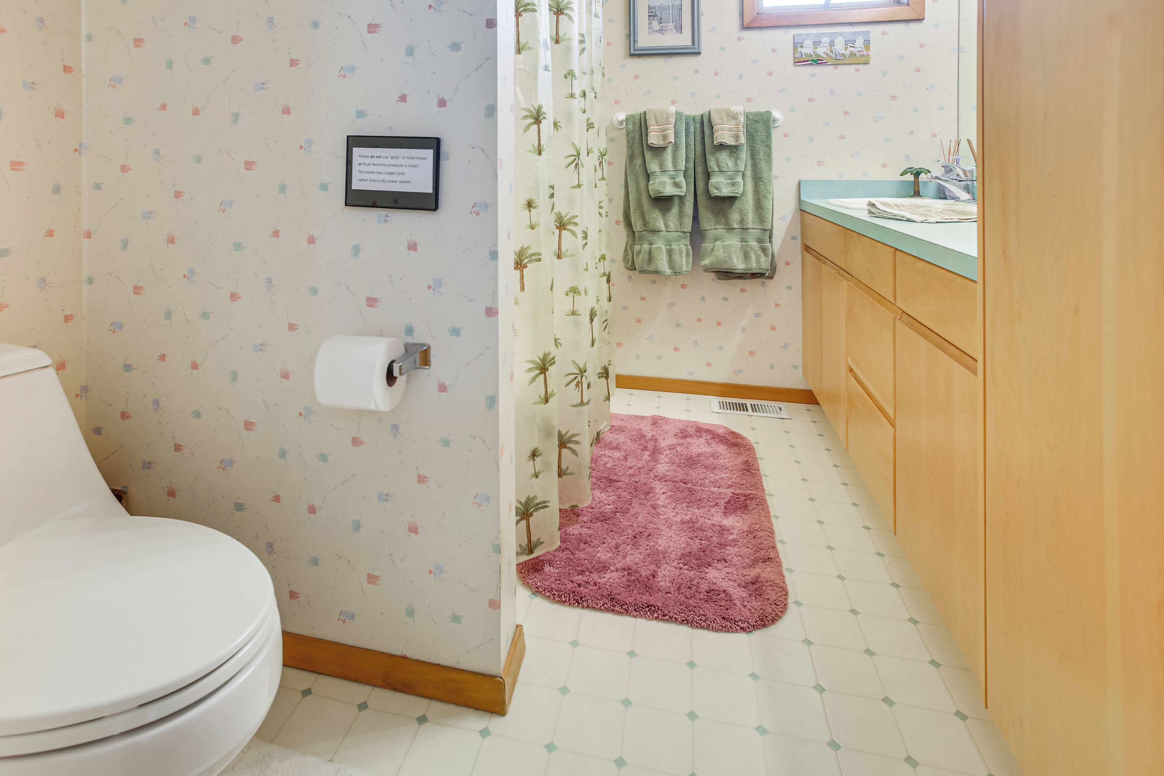 A bathroom with a toilet, a shower curtain, a sink, and a mirror.