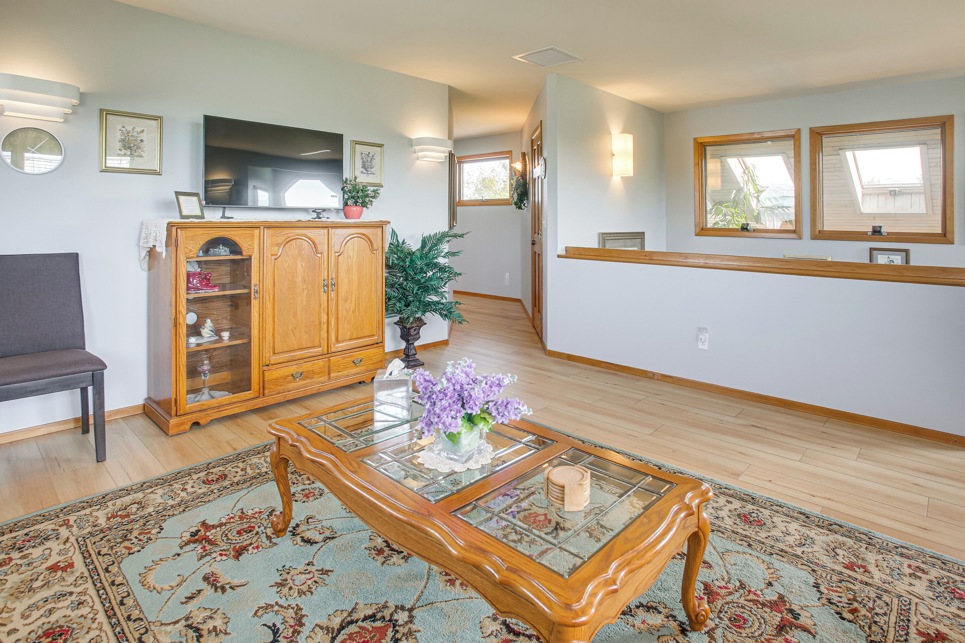 A living room with a wooden cabinet, a glass coffee table, a sofa, and a patterned rug.