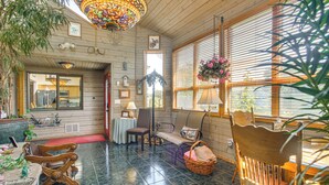 A cozy room with wooden walls, a tiled floor, a sofa, a chair, a table, and a hanging plant. - Unique Home w/ Beautiful Mtn Views! (Sequim)