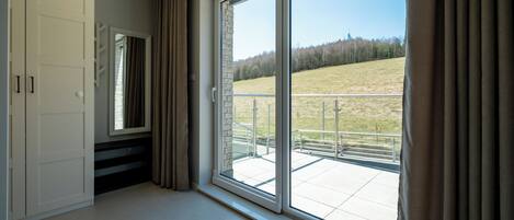 A room with a large sliding glass door leading to a balcony with a metal railing.