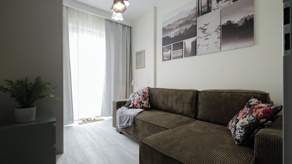 A living room with a sofa, a potted plant, and a wall with framed pictures. - Sun & Snow Magiczny Horyzont (Wisla)