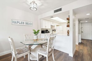 A modern kitchen with white cabinetry, a glass island, and a sign reading "NAPLES BEACH". - B-116 - Resort Views and Close to the Lobby (Naples)