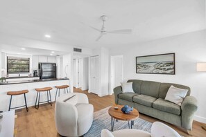 A modern living room with a green sofa, a coffee table, and a painting on the wall.