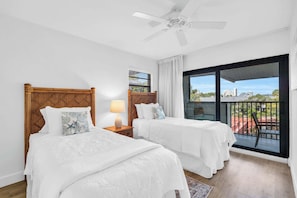 A hotel room with two beds, a ceiling fan, a balcony with a view, and a window with blinds. - F-335 - Modern Interior, 3rd Floor, Privacy (Naples)
