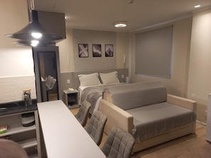 A compact hotel room with a bed, a sofa, a dining table, and a kitchenette. - Get a Flat 411 - Jardim Paulista (São Paulo)