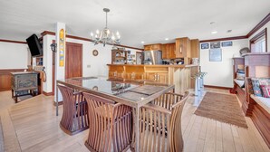 Una cocina amplia con armarios de madera, una isla central con sillas y un candelabro.