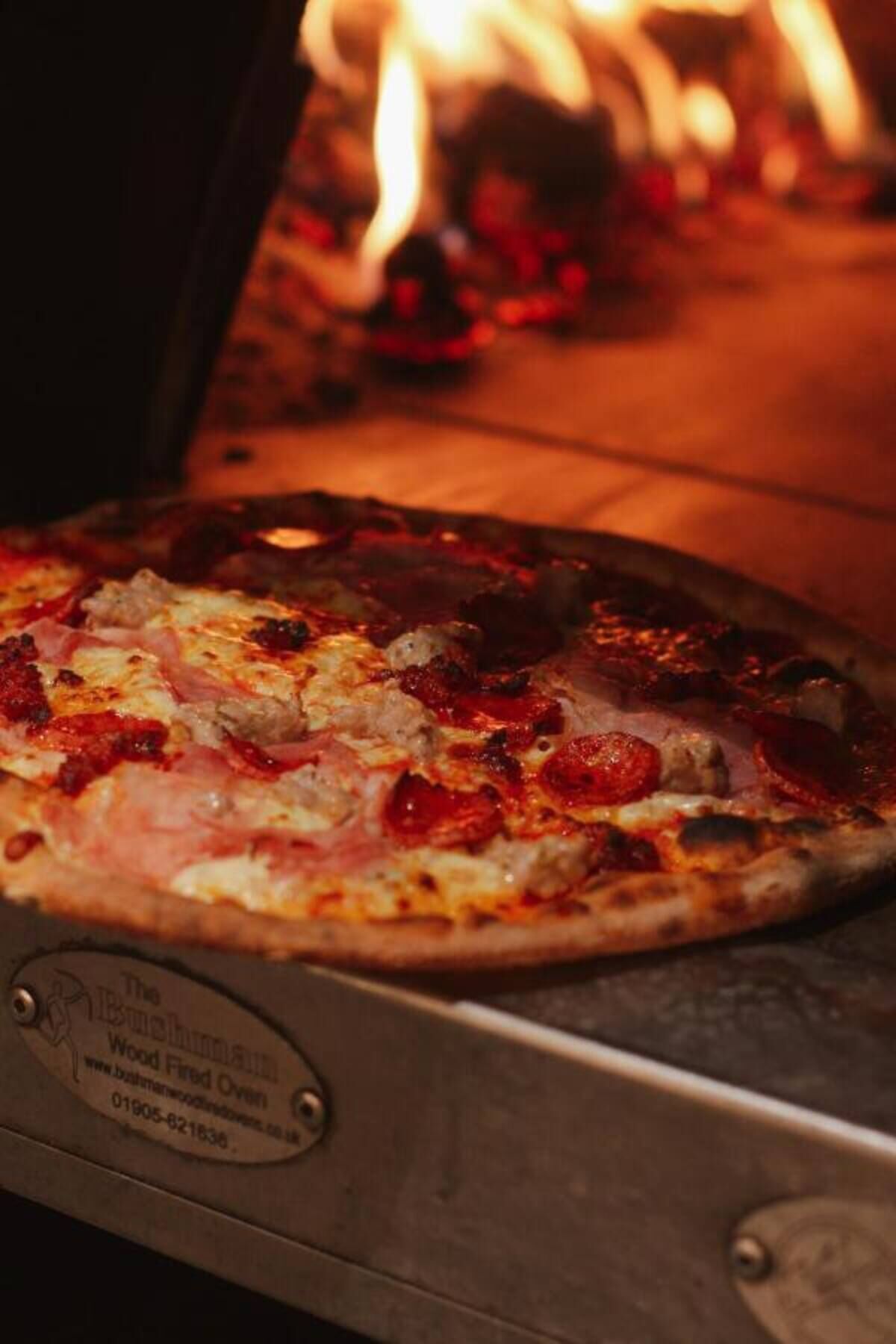Eine Pizza in einem Holzofen.