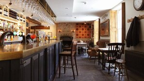 Una zona de bar con pared de ladrillo, sillas de madera y un reloj en la pared.