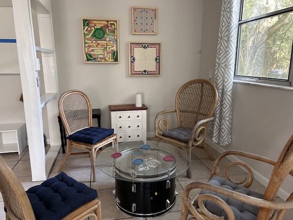 A cozy room with wicker chairs, a glass coffee table, and a white dresser.