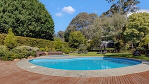 Una piscina con muelle de madera, rodeada de vegetación exuberante y árboles.