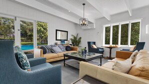 Una sala moderna con una mesa de centro de vidrio, sofás de cuero y sillones azules.