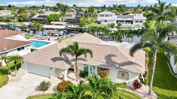 A residential area with a swimming pool, palm trees, and houses.