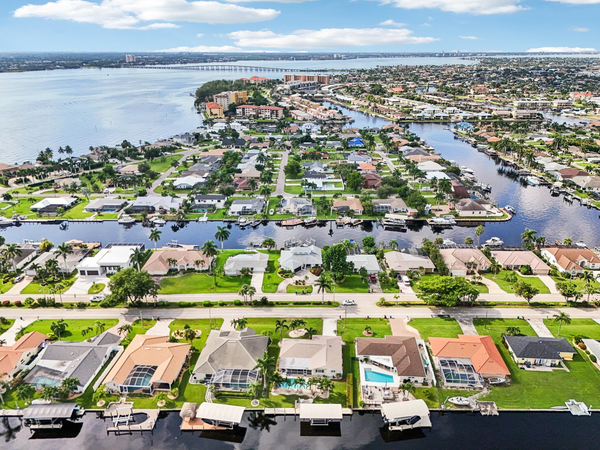 An aerial view of a residential area with houses, a marina, and a bridge in the background.