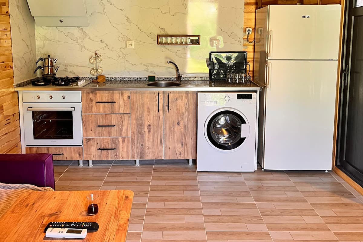 Une cuisine compacte avec des meubles en bois, un four encastré, un lave-linge et un réfrigérateur.