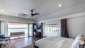 A modern hotel room with a large bed, a desk, a chair, and a television. There is a balcony with a view of the water. - Trilogy Villas Denarau (Nadi)