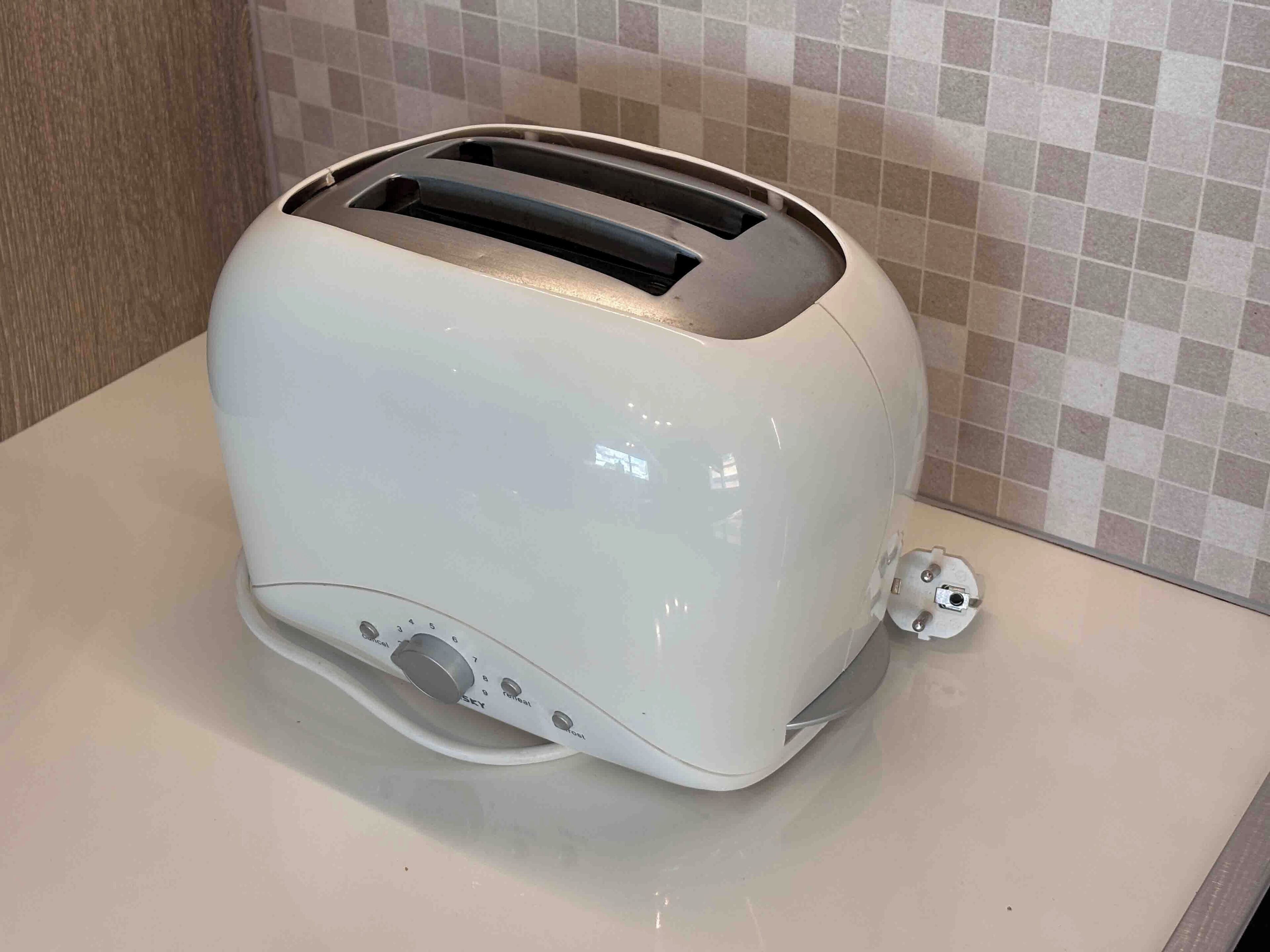 Un tostapane bianco su un piano di lavoro della cucina, con uno schienale piastrellato.